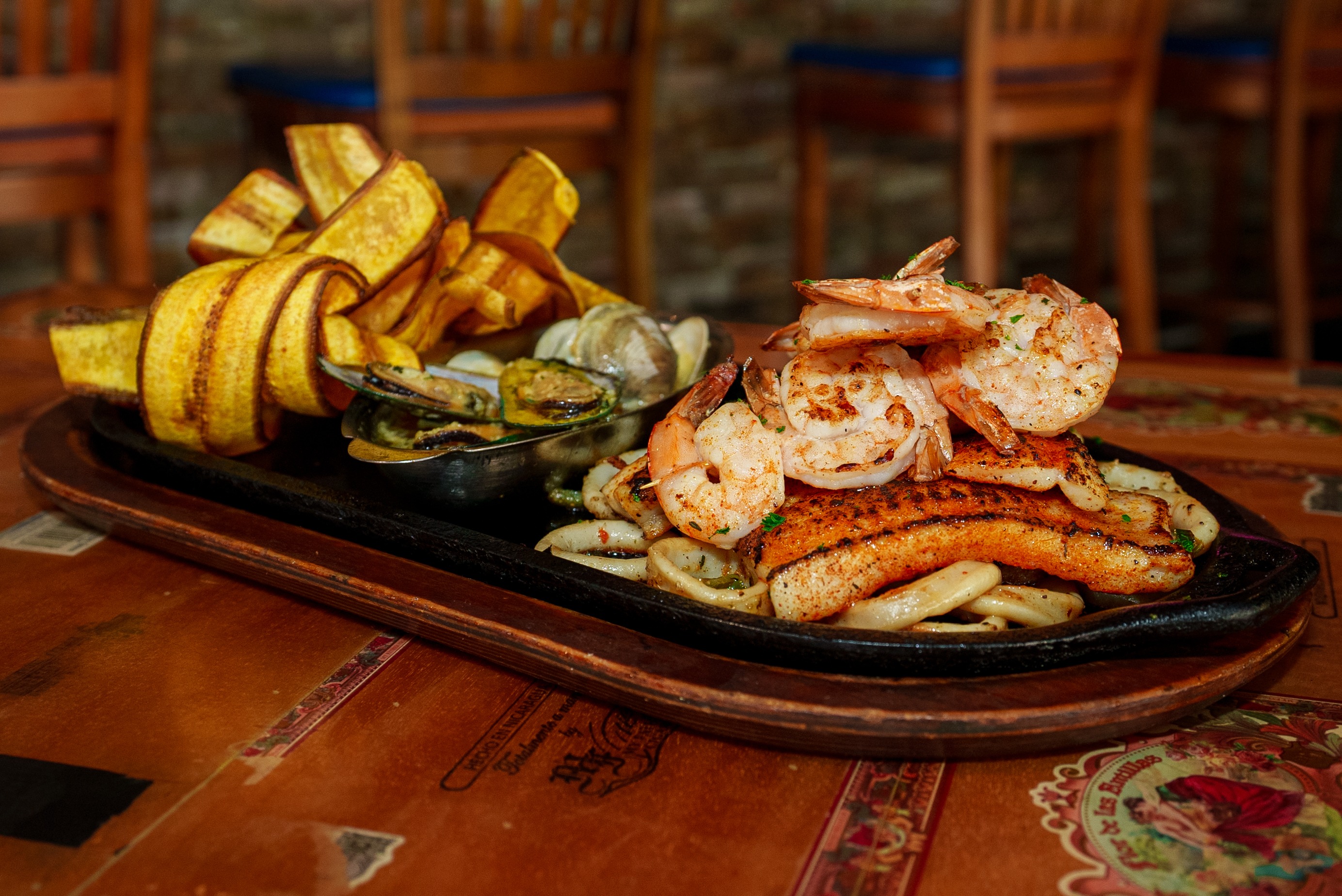 Sizzling seafood platter with grilled shrimp, fish, calamari, mussels and plantain chips